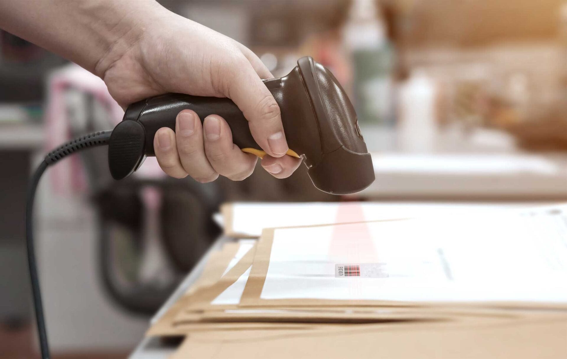 Die Hand eines Lagerarbeiters scannt den Strichcode eines Pakets